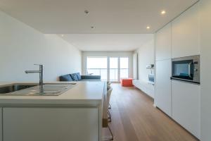 a white kitchen with a sink and a living room at Apartment Sea View in Middelkerke