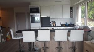 a kitchen with white chairs and a black counter top at Télérésidence in Crans-Montana