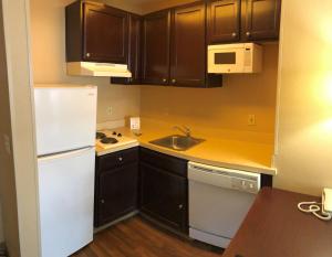 uma pequena cozinha com armários castanhos e um frigorífico branco em Extended Stay America Suites - Austin - North Central em Austin