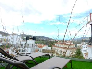 een balkon met tafels en stoelen en uitzicht op de stad bij Loft El Sueño in Cómpeta