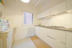 uma cozinha com armários brancos e uma janela em DolceVita Apartments N 396 em Veneza