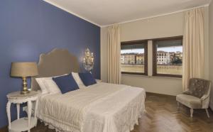 a bedroom with a bed and a chair and a window at the river in Pisa