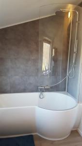 een badkamer met een wit bad en een douche bij La petite maison in Aywaille