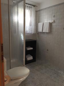 een badkamer met een douche, een toilet en handdoeken bij Green View Apartments in Contra