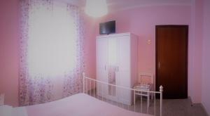a bedroom with pink walls and a bed and a cabinet at Hotel Ristorante El Caracol in Mulazzo