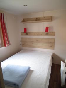 a small bedroom with a white bed and wooden shelves at Camping La Pindière in Héric