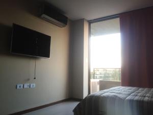 a bedroom with a bed and a television on the wall at Condominio del alto 3 in Rosario +29 photos