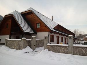 a wooden house with snow in front of it at Penzión Zemanov dvor in Lietavská Svinná