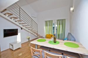 ein Esszimmer mit einem Tisch, Stühlen und einer Treppe in der Unterkunft Apartments Roses Stobrec in Split