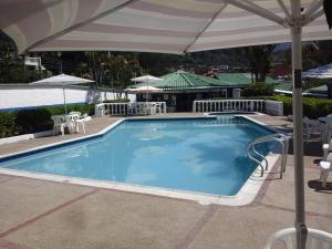 una gran piscina con sombrilla y mesa al aire libre en Hotel Villa Paz, en San Francisco