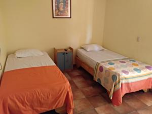 a room with two beds and a small cabinet at Hotel Loro Tuerto in Santa Cruz de Barahona