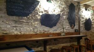 a bar with a stone wall with a table and stools at Hotel Rural Grado del Pico in Grado del Pico