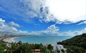 uma vista para uma praia com um céu azul e nuvens em Apart Hotel Margherita em Natal