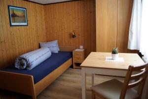 a small bedroom with a bed and a table at Hotel Alpenblick Muotathal in Muotathal