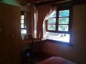 1 dormitorio con ventana con silla y escritorio en Casa Los Robles, en San Martín de los Andes