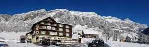 ein Gebäude im Schnee vor einem Berg in der Unterkunft Hotel Alpenblick Muotathal in Muotathal