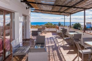 Un patio con mesas y sillas y el mar. en Hotel Rural Almazara, en Frigiliana