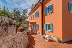 a building with blue windows and a stone wall at Apartmani Villa Casper in Veli Lošinj