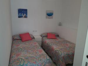 エル・プエルト・デ・サンタマリアにあるApartamento faro Puerto Sherryの赤い枕が備わる小さな部屋のベッド2台