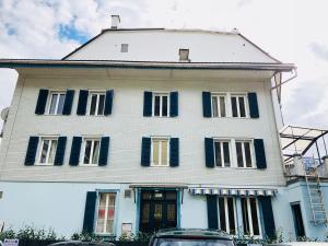 duży biały dom z niebieskimi okiennicami w obiekcie Interlaken Linda Inn Lodge w mieście Interlaken