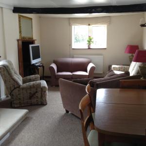 a living room with couches and chairs and a television at Ockhams Farm Guest House in Edenbridge
