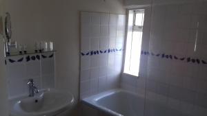 bagno con lavandino, vasca e finestra di Ockhams Farm Guest House a Edenbridge
