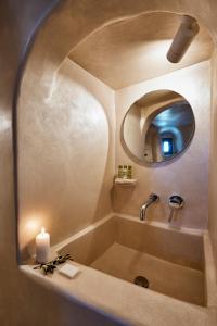 een badkamer met een bad met een kaars en een spiegel bij The Small Architect's House in Pirgos