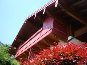 un edificio con un balcón rojo sobre un árbol en Alpen-Chalet-Sol-Alpium, en Reit im Winkl