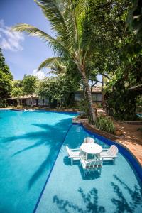 a pool with chairs and a table and a palm tree at Sombra e Água Fresca Resort in Pipa