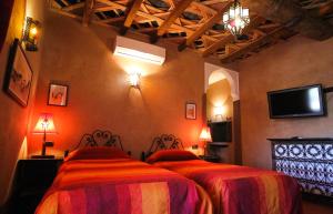 a bedroom with two beds and a flat screen tv at Dar Amoudou in Ouarzazate