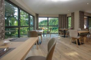 a dining room with tables and chairs and large windows at Apartment Hotel Christine in Avelengo