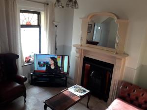 een woonkamer met een tv en een open haard bij Titanic Sailortown Belfast City Centre townhouse in Belfast