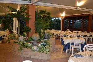 a restaurant with white tables and white chairs and plants at La Villa dei Gourmets - Struttura Sanificata in Foggia