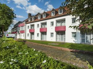a row of white apartment buildings with red balconies at Andante Hotel Erding in Erding