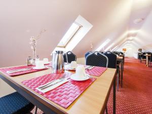 uma sala de jantar com mesas e cadeiras e uma janela em Andante Hotel Erding em Erding