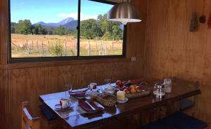 - une table avec des fruits dans une chambre avec une fenêtre dans l'établissement Refugio de montaña El Huape, à Curacautín