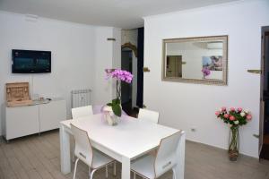 a white dining room with a white table with flowers on it at Bijoux de Rome Apartment Vatican in Rome