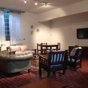 a living room with chairs and a couch and a flat screen tv at Posada los Cedros in La Cumbre