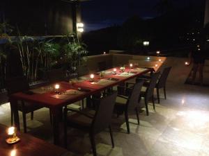 a long wooden table and chairs on a patio at night at The Puncak Lombok in Senggigi