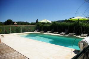 a swimming pool with chairs and an umbrella at chez gallon chambres d’hôtes in Vézac