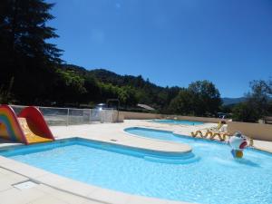 uma piscina com dois escorregas e um parque aquático em Les maisonnettes de bonneval em Jaujac