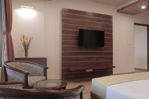 - une chambre avec un lit et une télévision murale dans l'établissement Jai Hotels, à Darjeeling