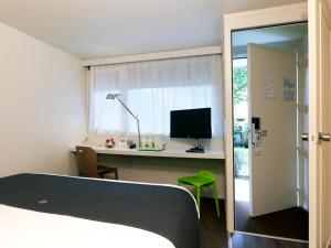 a bedroom with a bed and a desk with a computer at Campanile Hendaye in Hendaye