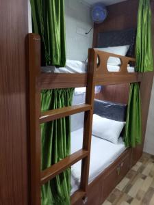 two bunk beds in a room with green curtains at Royal Dormitory in Mumbai