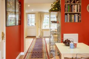 a living room with orange walls and a white table at Jasmine Cottage in Kelsale