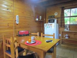 cocina con mesa de madera y nevera en Cabañas Ñuke Mapu en Villa Ventana