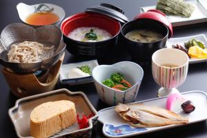 einen Tisch mit Teller mit Lebensmitteln und Schüsseln mit Lebensmitteln in der Unterkunft Kinosaki Yamamotoya in Toyooka