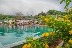 a pool at a resort with yellow flowers in the foreground at PP Charlie Beach Resort- SHA Plus in Phi Phi Islands