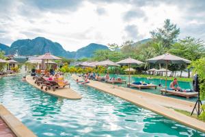uma piscina num resort com pessoas sentadas em bancos em PP Charlie Beach Resort em Phi Phi Don