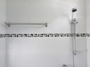e bagno con doccia e parete piastrellata bianca. di Merdeka Guest House 2 a Kuching